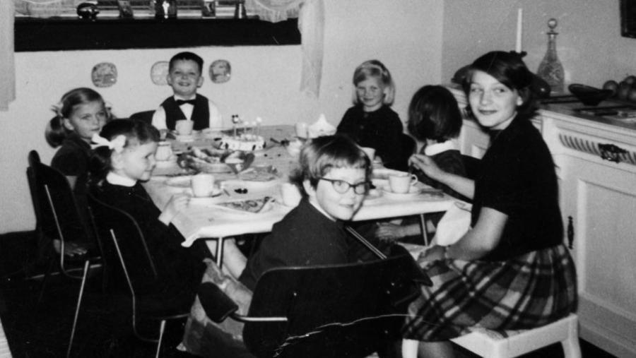Børn fra gamle dage spiser rundt om et bord