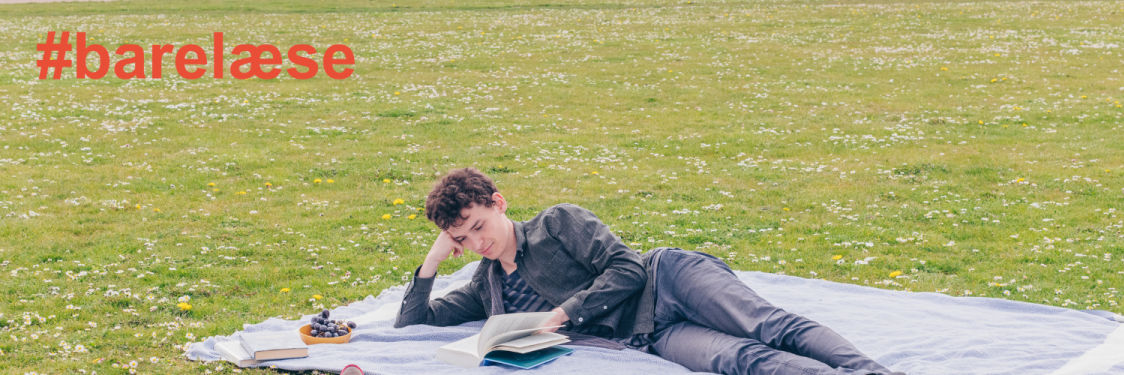 Mand ligger på græs og læser